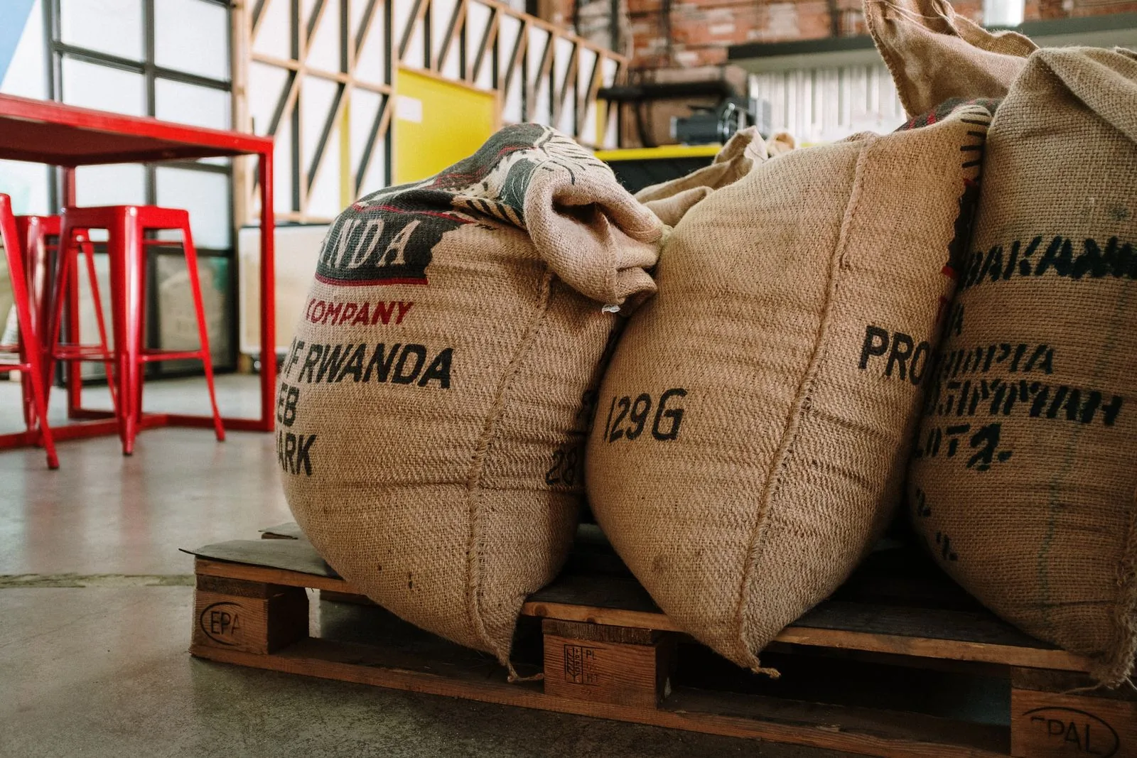 Trois sacs de jute pansus posés sur une palette, portant les mentions « Rwanda » et « Ethiopia » et des numéros de lot.