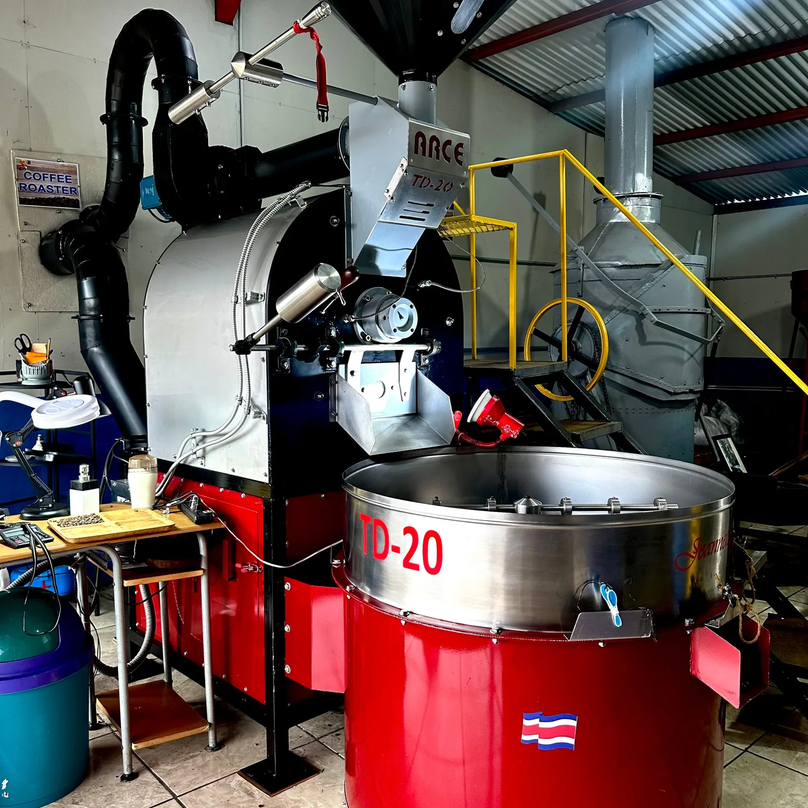 Un torréfacteur industriel rouge et argenté de modèle TD-20, équipé d'un large bac de refroidissement rotatif, installé dans un atelier
