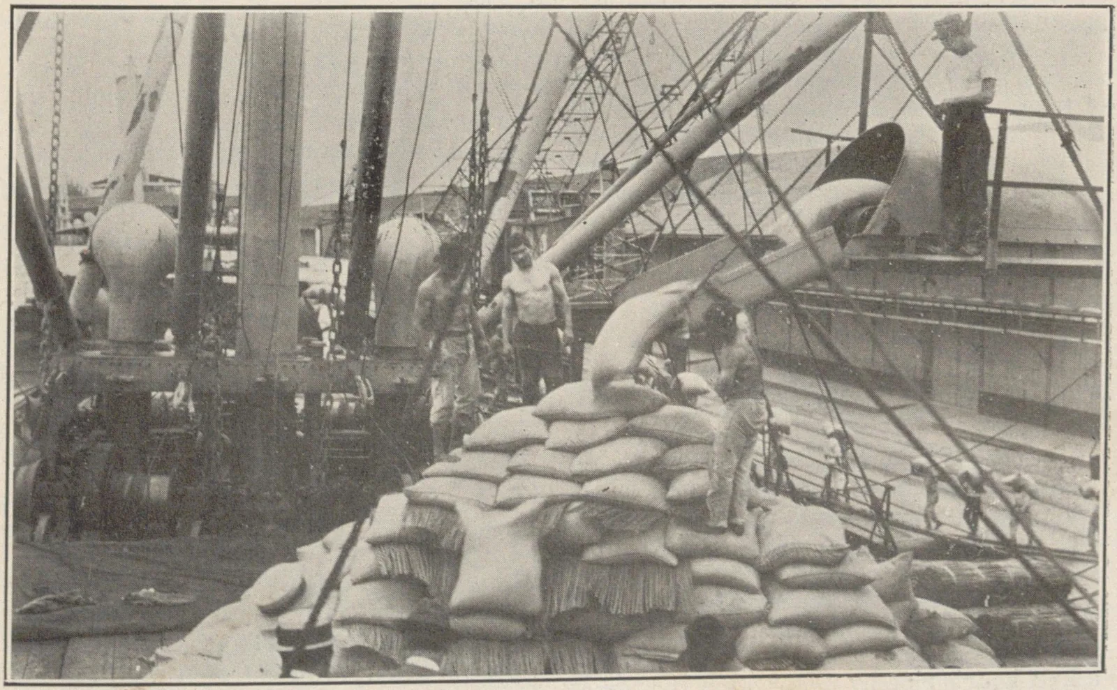 Des dockers empilent des sacs de café sur le pont d'un navire, sous les mâts de charge et les palans.