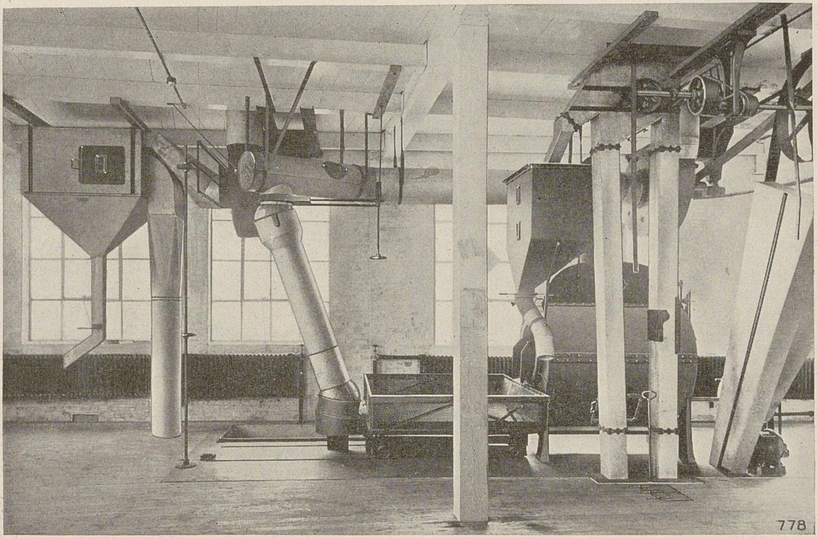 Vue d'un étage d'usine où des trémies et des goulottes descendent vers les machines de torréfaction.